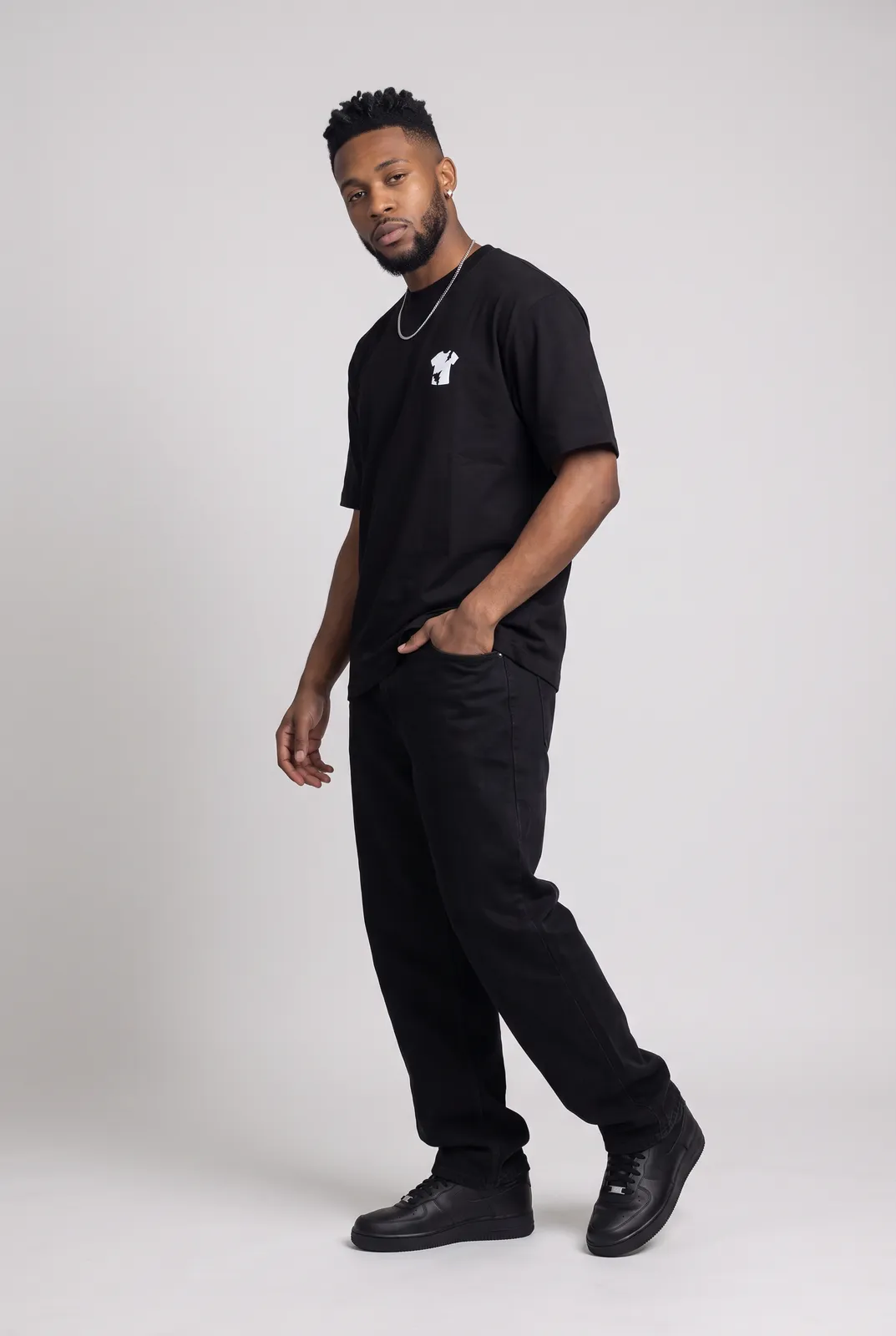 Malik Carter wearing the BLACKOUT Oversized in Black, three quarter lean