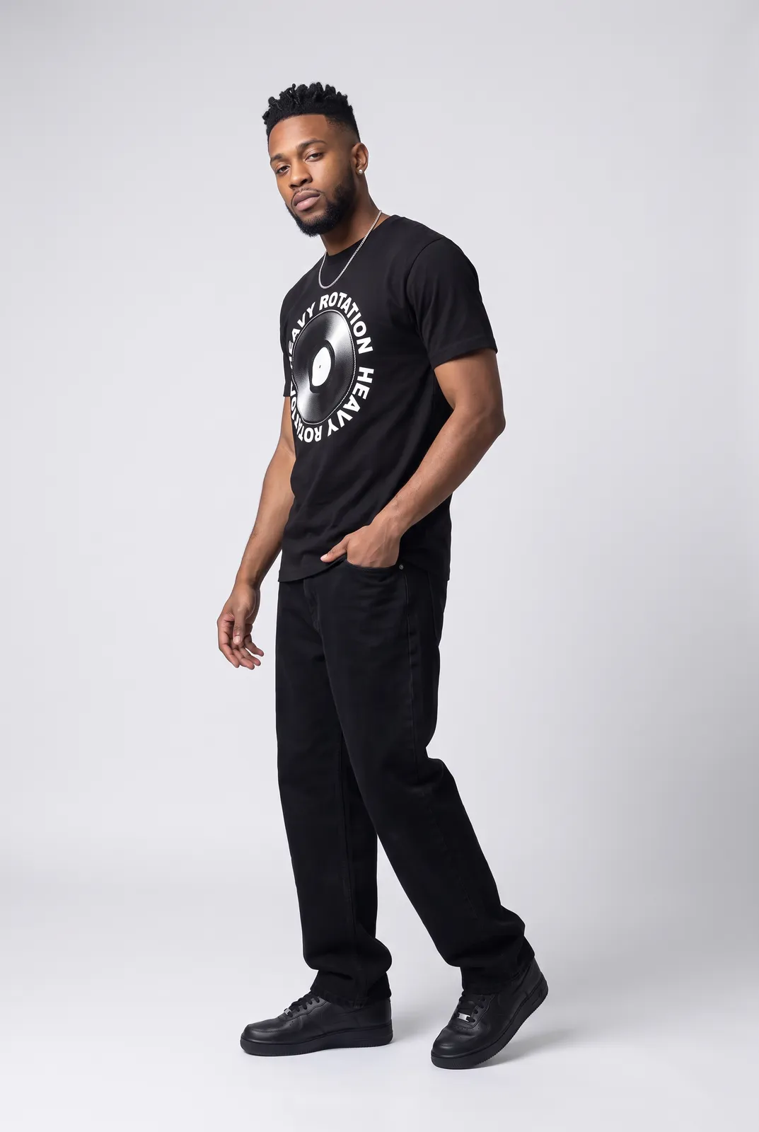 Malik Carter wearing the HEAVY ROTATION Tee in Black, three quarter lean